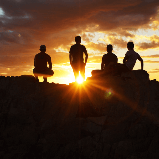 A beautiful sunset over a group of people standing on a rocky peak, enjoying nature's beauty together