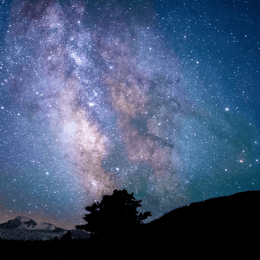 Starry night sky with a multitude of stars shining brightly over the mountain range.