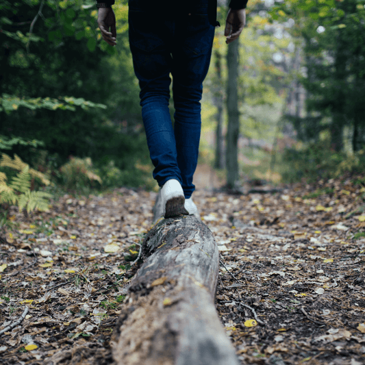 Outdoor safety tip: Practice balance on a tree trunk to improve stability and avoid falls during wilderness exploration - person balancing on tree trunk