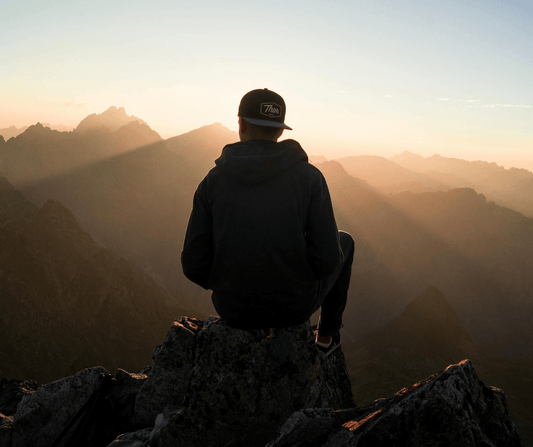 A solitary hiker enjoys the majestic mountain views at sunset, embracing the serenity of solo camping adventures.