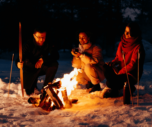 Group of friends enjoying a campfire in the snow during winter camping trip