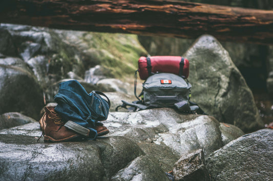 Two hiking backpacks resting on a rock in a dense forest
