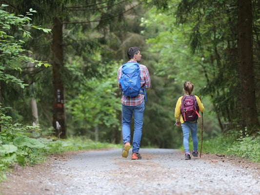 A loving father and daughter enjoy a nature walk through the forest, exploring and learning about the natural world around them