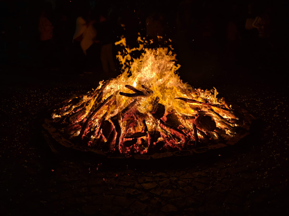 A cozy campfire scene with orange and red flames, crackling logs, and a group of people sitting around enjoying the warmth and ambiance of the fire